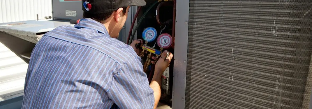 HVAC technician servicing a condenser unit in Clearfield